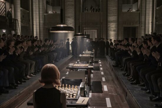 Cenário marrom e escuro de uma partida de xadrez, com Beth senteda de costas com um tabuleiro na frente