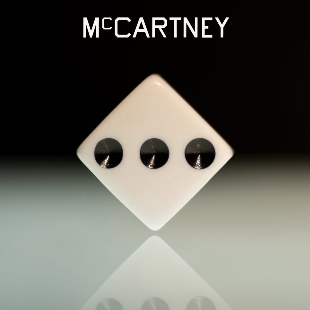 Capa do álbum McCartney III. Um fundo preto com um dado ao centro e escrito "McCartney" na parte superior.