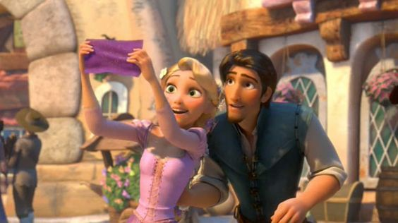 A imagem mostra Rapunzel, de vestido lilás e cabelos trançados, segurando uma pequena bandeira roxa. Atrás dela está Flynn Rider, de camisa branca e colete azul, olhando curioso. Ele tem os cabelos castanhos curtos e lisos.