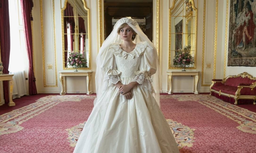 Na imagem, Lady Di, jovem de cabelos curtos e loiros, usa um vestido de noiva branco, volumoso.
