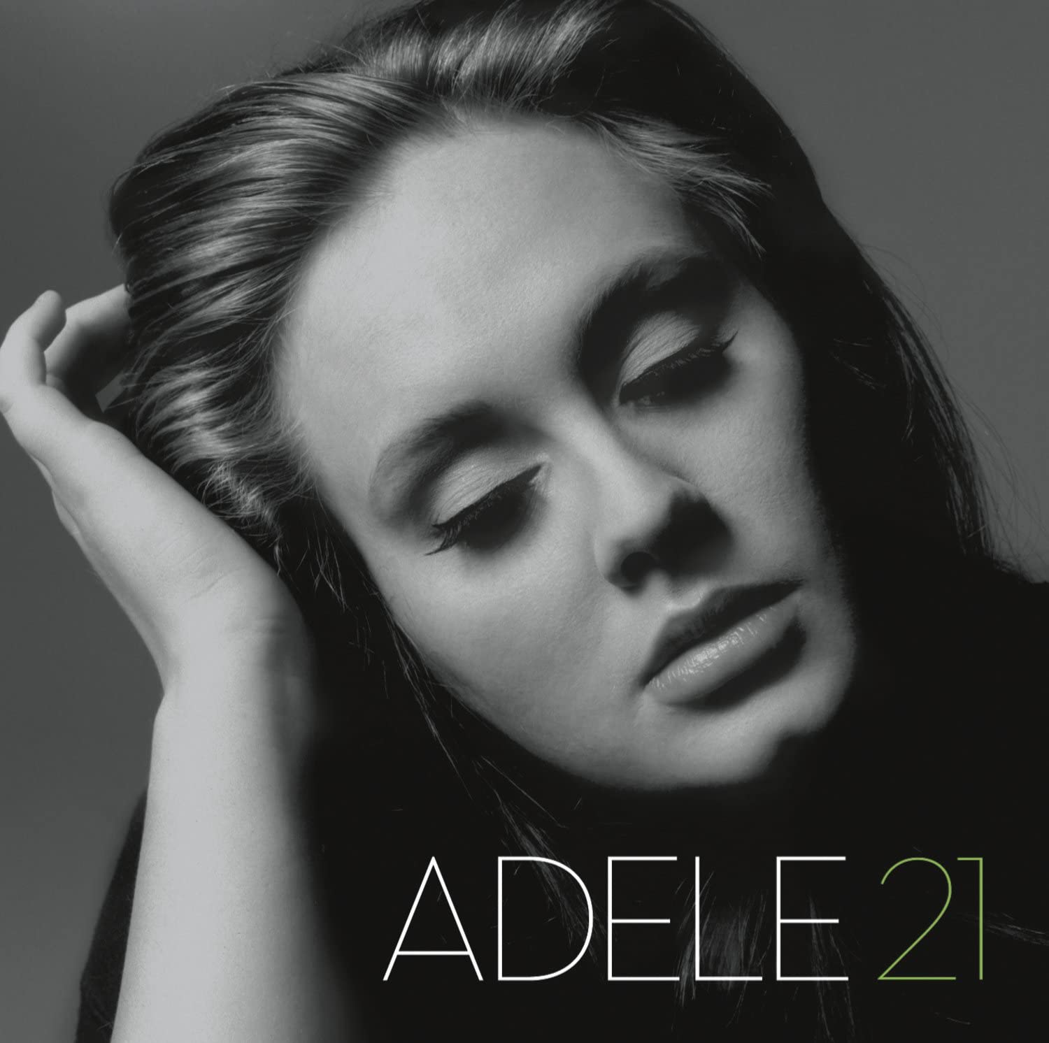 Capa do álbum 21 da Adele. Ele mostra o rosto da cantora de olhos fechados. Ela tem os cabelos soltos e penteados para trás, pele clara e a mão apoiando a cabeça. A imagem é em preto e branco com o número 21 em verde.
