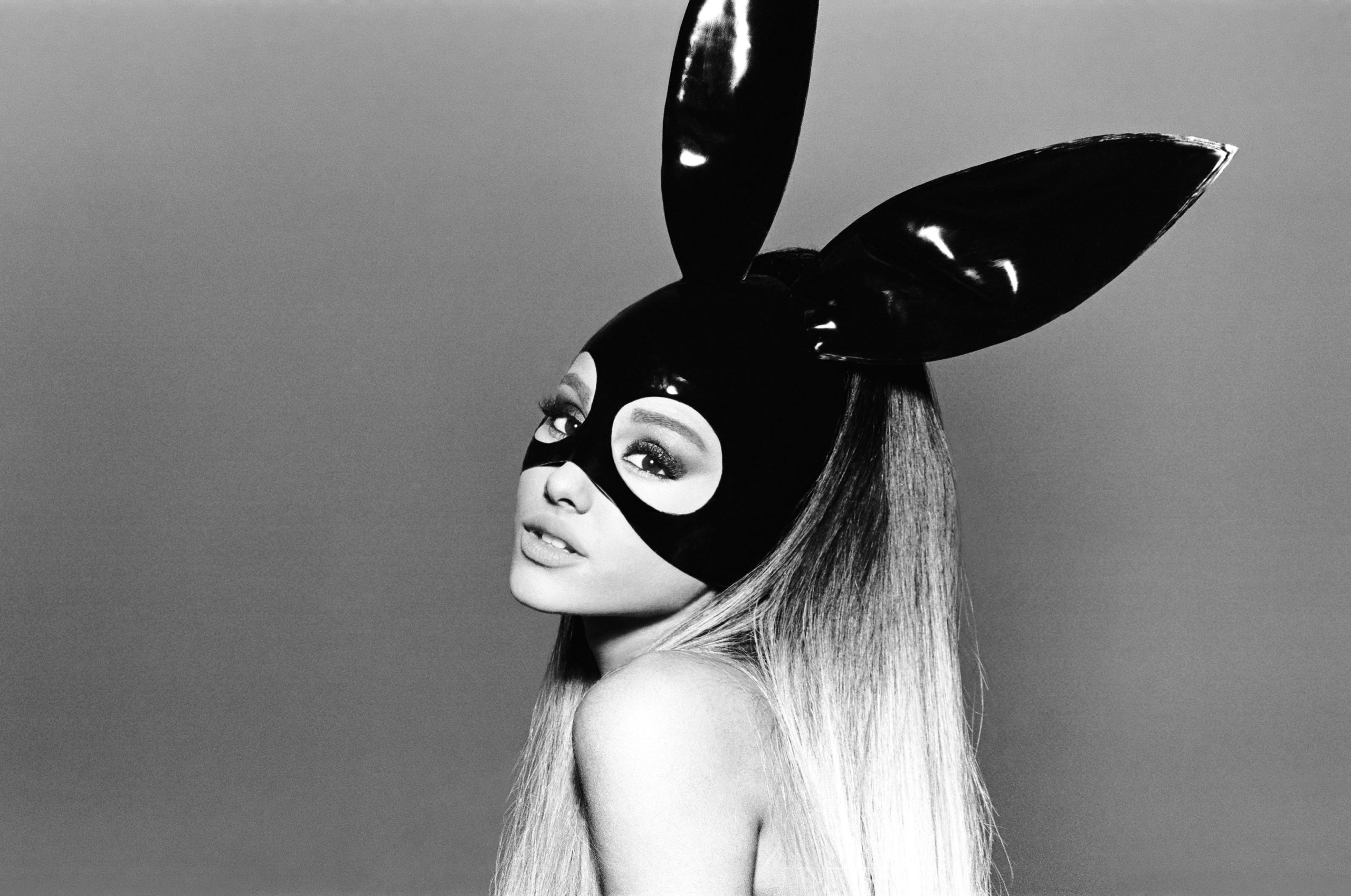 Capa do álbum Dangerous Woman. Ariana Grande se revela na imagem, de tronco para cima, inclinada para o lado. A imagem está em preto e branco. Ariana é uma mulher branca, de cabelo castanho claro. Ela usa um vestido de látex preto e uma máscara preta com orelhas de coelho.