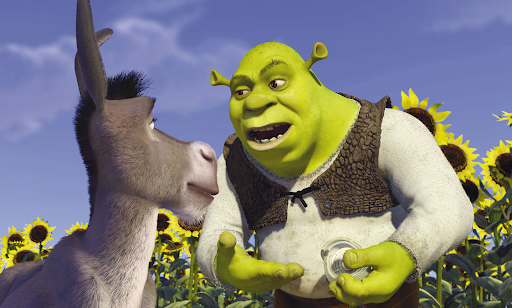 Shrek e Burro em uma cena que ambos estão conversando ao redor de uma plantação de girassóis. Shrek está com uma cebola na mão.