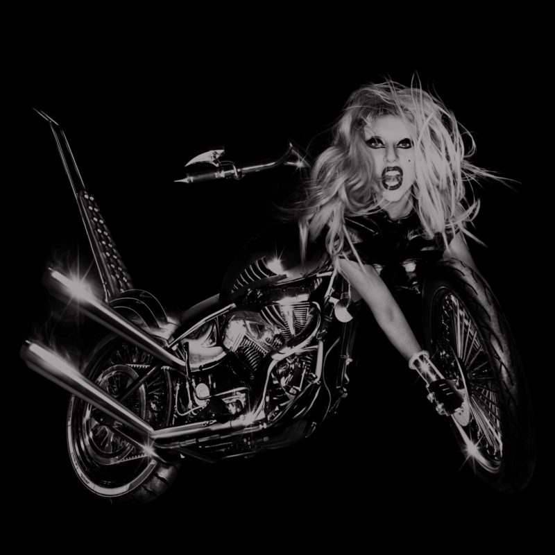 Capa do álbum Born This Way, de Lady Gaga. A imagem mostra Lady Gaga como metade moto metade mulher, num fundo preto. Ela está de cabelos platinados e usa batom.