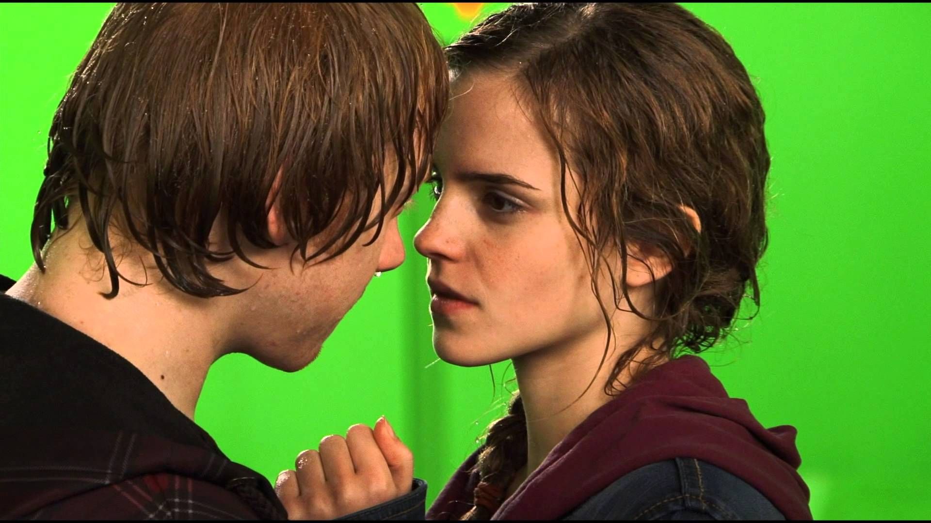 Cena do filme Harry Potter e as Relíquias da Morte: Parte 2. A cena nos bastidores do filme mostra a tela verde ao fundo, e no foco estã um close-up de Rony e Hermione, depois da gravação do beijo deles. Os dois são brancos, Rony é ruivo e Hermione tem o cabelo castanho claro. Eles estão molhados e se olham nos olhos.