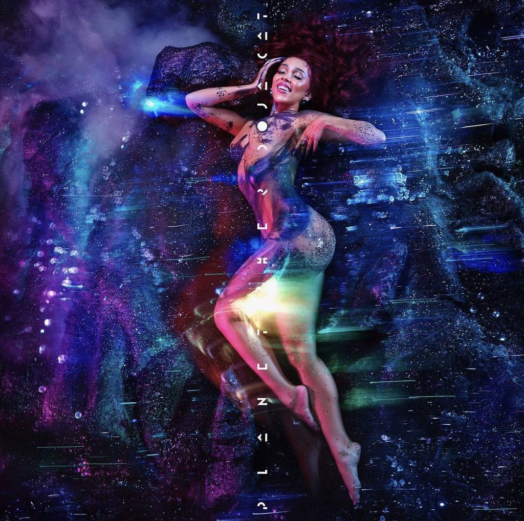 Capa do álbum Planet Her, da cantora Doja Cat. A foto mostra a cantora Doja Cat, uma mulher negra de olhos castanhos e cabelos vermelhos, e ela está deitada de lado. Ao fundo há a representação do espaço sideral.