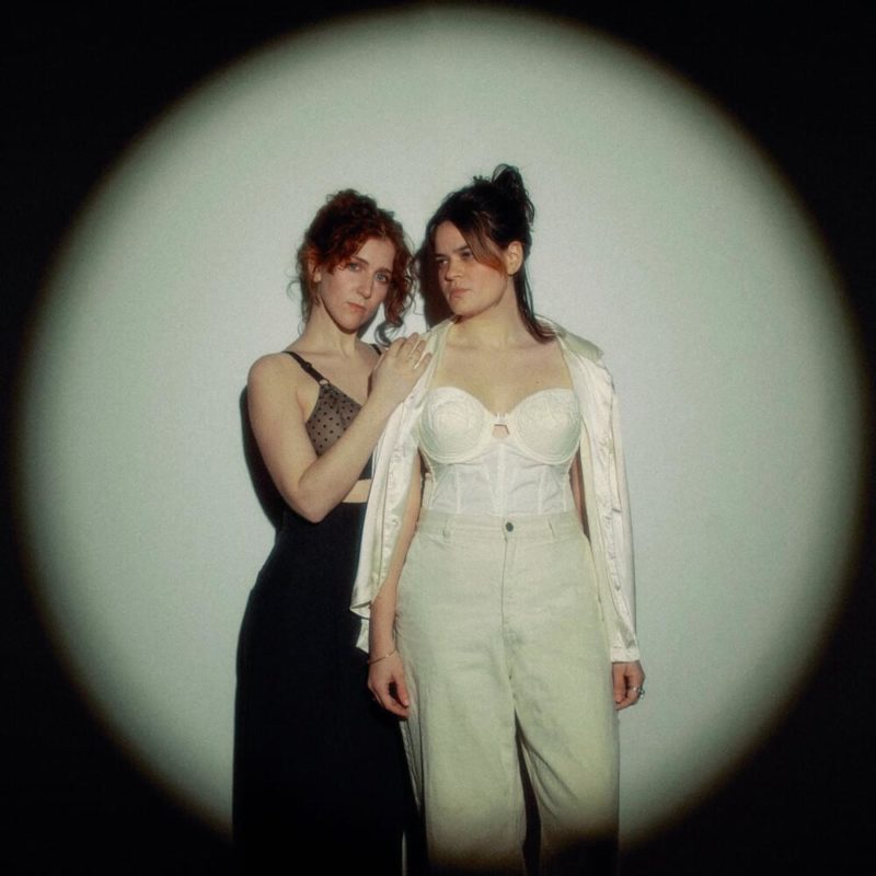 Capa do EP Used To Be Scared Of The Dark, do duo Overcoats. A foto mostra as duas cantoras, no escuro mas iluminadas por um holofote redondo. O fundo iluminado é branco.