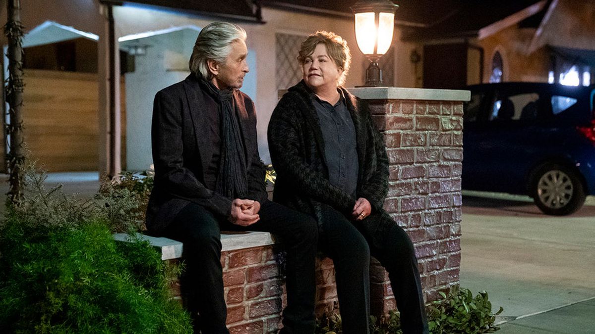 Cena da série O Método Kominsky. Nela, vemos Sandy e Roz sentados em uma mureta na rua, à noite. Eles são idosos, brancos e se olham nos olhos.
