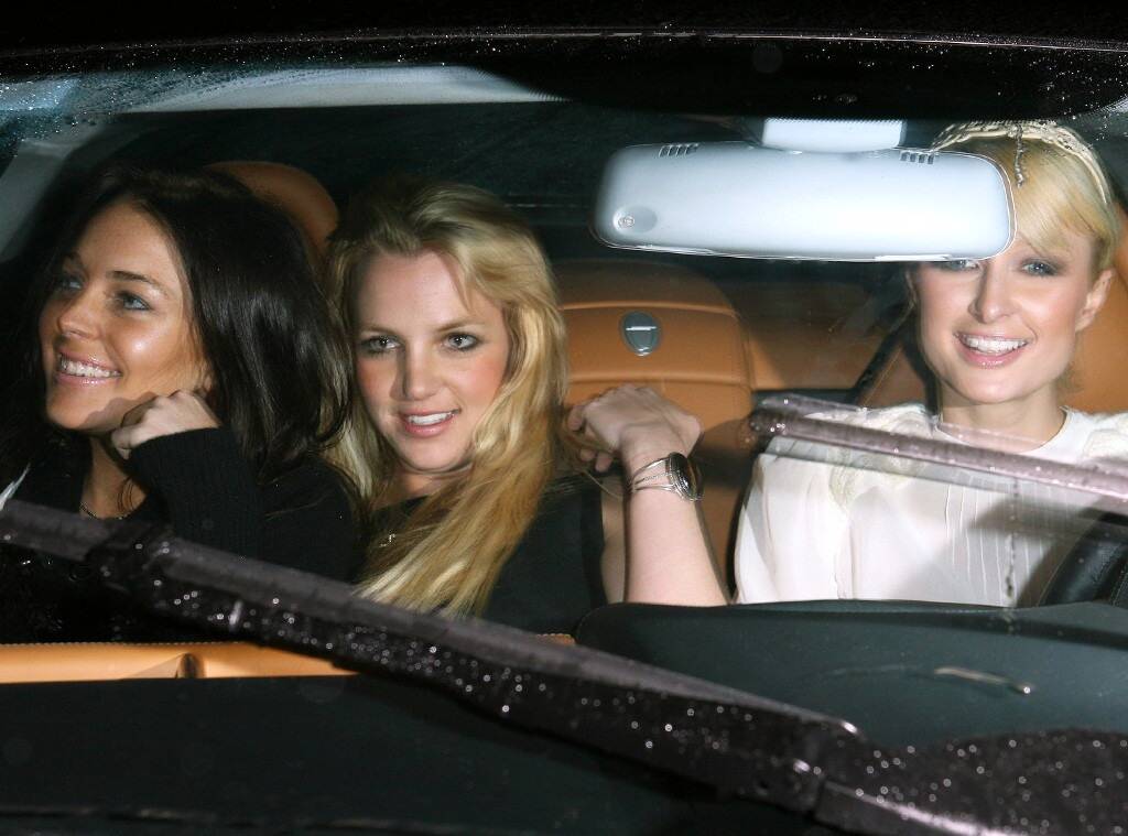 Foto de três mulheres em um carro: Lindsay Lohan, Britney Spears e Paris Hilton. Lindsay é branca e seu cabelo é preto, Britney e Paris são brancas e seus cabelos são loiros. A foto é tirada perto do para-brisa do carro, que tem o estofado laranja. Todas estão sorrindo.