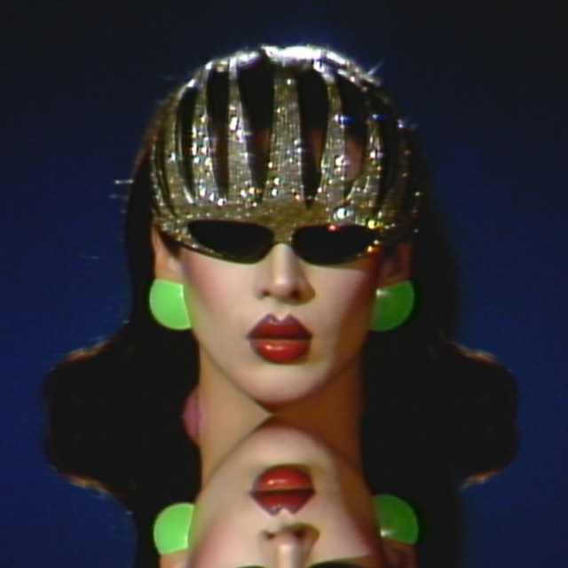 Capa da música Mistress Violet, de Allie X e Violet Chachki. A foto mostra Violet, uma drag queen branca e de cabelos pretos, óculos escuros, coroa prateada e brincos verdes, olhando para frente, com o reflexo do espelho abaixo dela. 