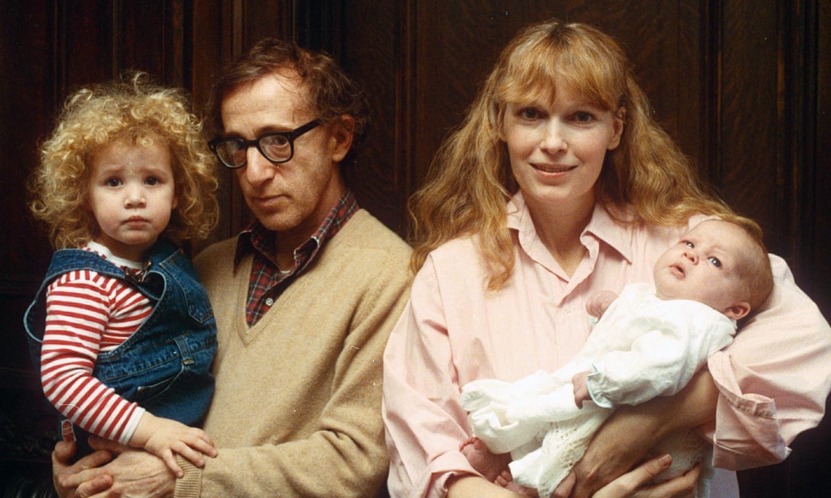 A imagem é uma foto de Woody Allen e Mia Farrow segurando no colo, respectivamente, Dylan e Ronan Farrow.
