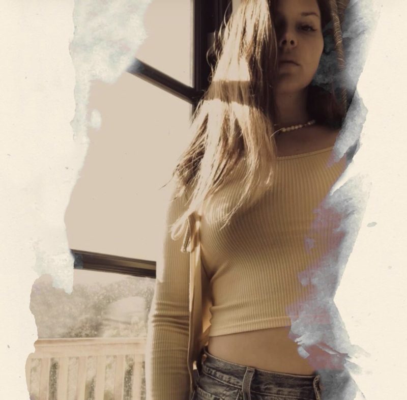 Capa do single Arcadia. A imagem é composta por uma foto da cantora Lana Del Rey. Branca de cabelos castanhos escuros, Lana veste calça jeans e uma blusa amarela. Ela se encontra no canto esquerdo da imagem, na frente de uma janela. As bordas da foto estão tampadas por uma fumaça branca.