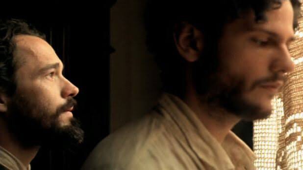 Cena do filme Lavoura Arcaica exibe dois homens brancos de cabelos castanhos curtos e barba, olhando pela janela.