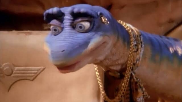 Cena da série A Família Dinossauros em que há um dinossauro fêmea azul usando colares e brincos.