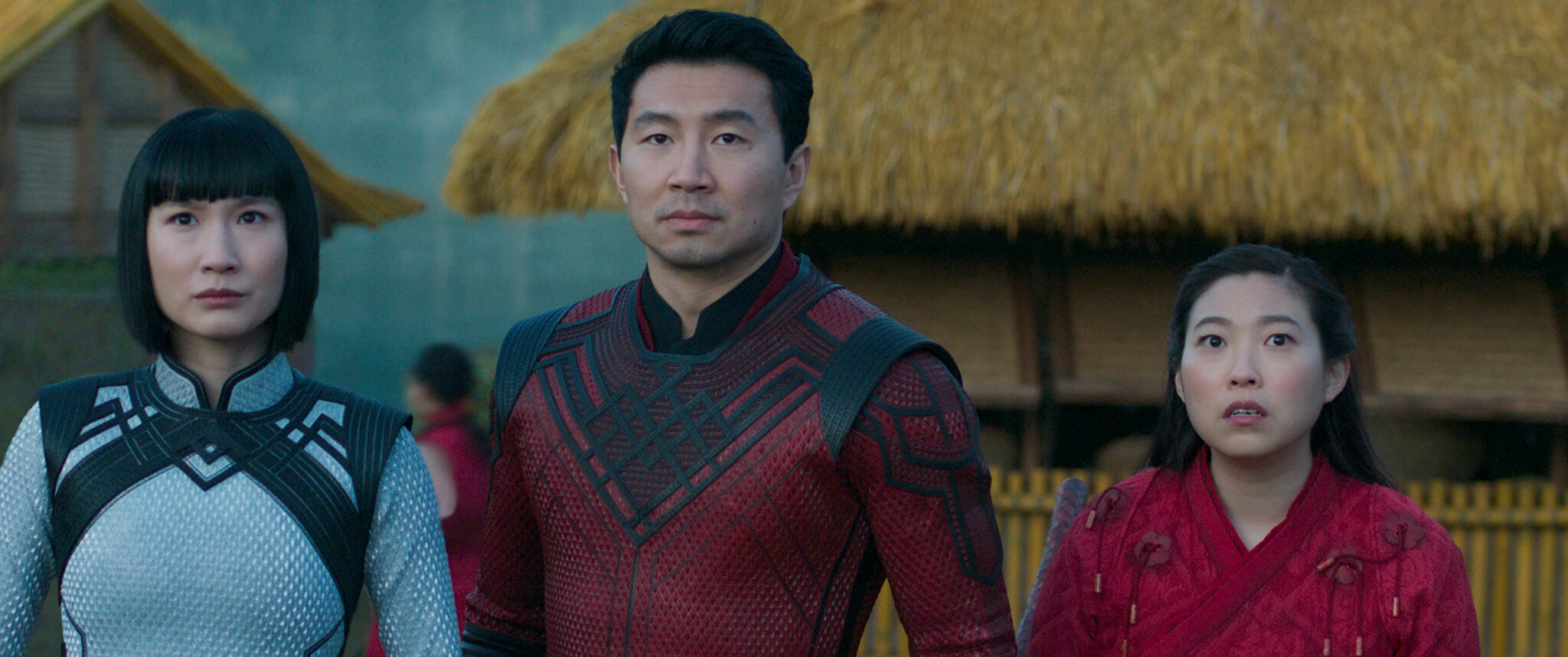 Cena do filme Shang-Chi e a Lenda dos Dez Anéis. A cena mostra 3 pessoas asiáticas em pé, usando roupas de guerra e olhando para frente com expressões de medo.