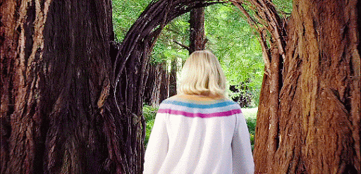 GIF da série The Good Place onde mostra uma mulher andando em uma floresta, em direção a um portal composto por árvores. 