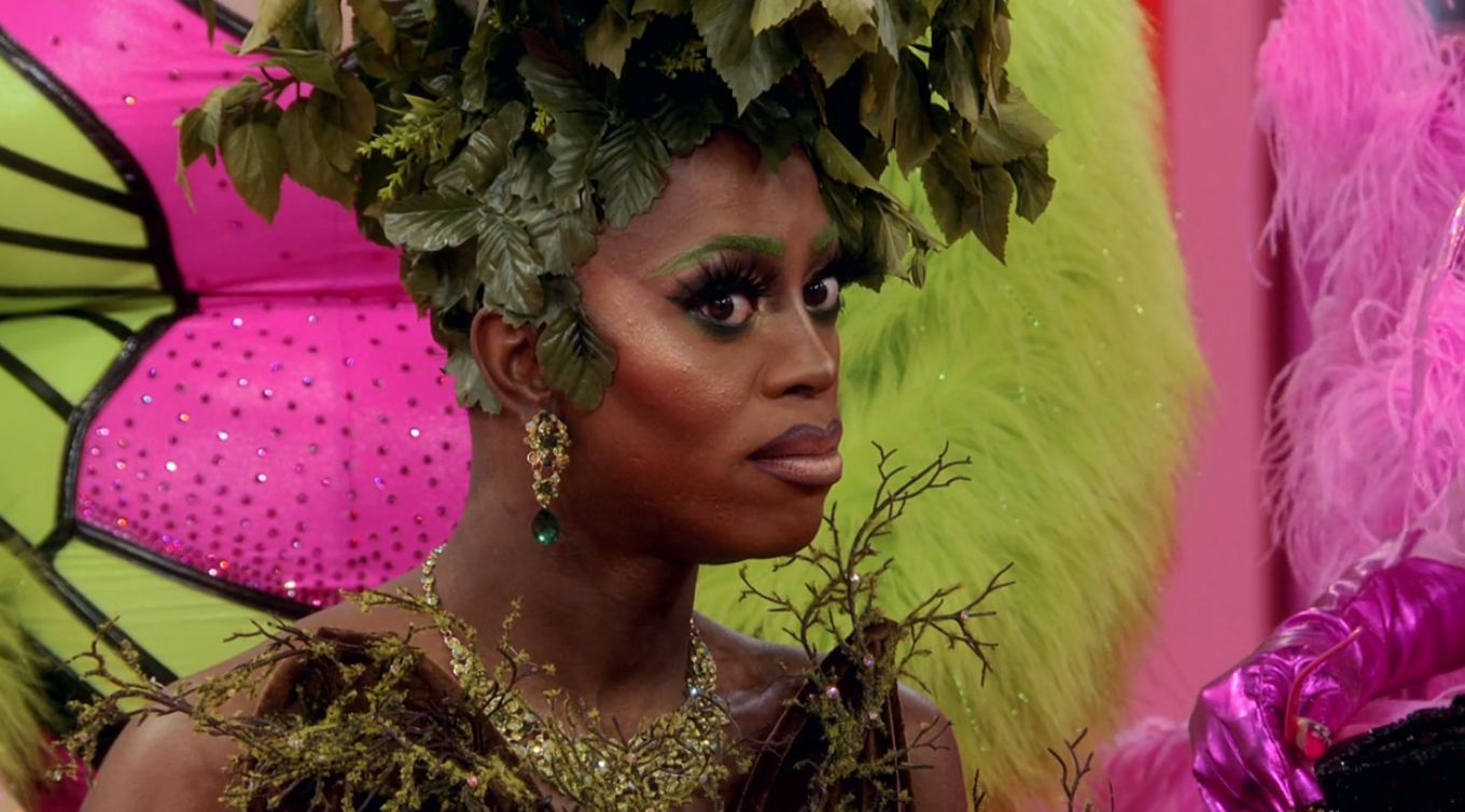Cena do reality show All Stars 6, mostra Ra'Jah O'Hara, uma drag queen negra, com expressão de preocupação. Ela usa uma roupa marrom, com detalhes que lembram folhas de uma árvore na cabeça e nos ombros.