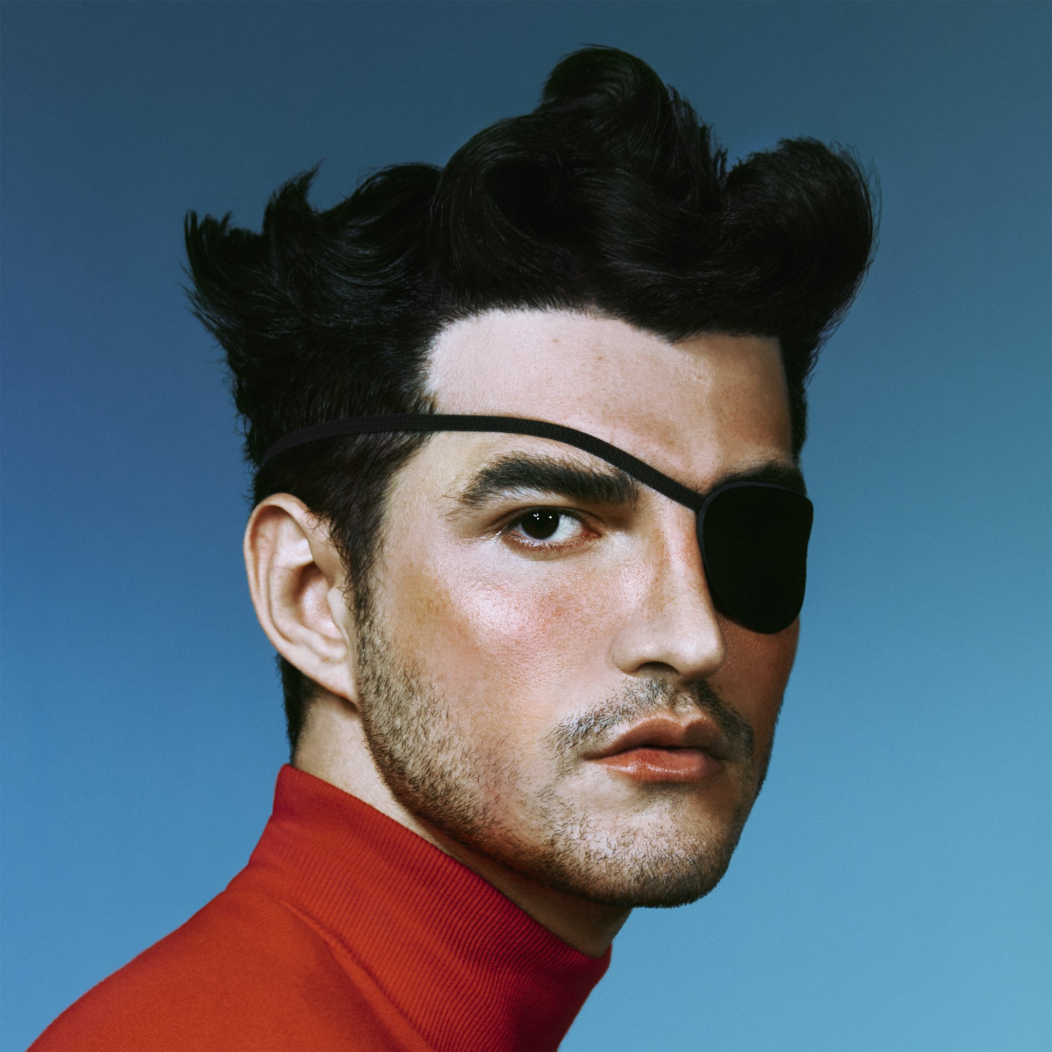 Capa do álbum Pirata. Jão, um homem jovem e branco, está posicionado ao centro da imagem. Ele está usando uma blusa vermelha de gola alta e um tapa-olho preto no olho direito. O fundo da foto é de cor azul clara.