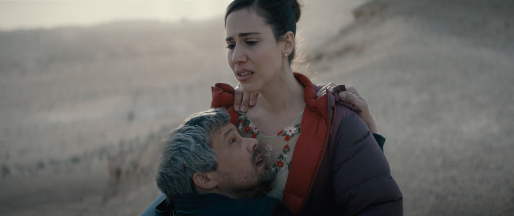 Cena do filme Ahed's Knee mostra um homem se jogando no colo de uma mulher, que tem uma expressão de dor e tristeza no rosto.