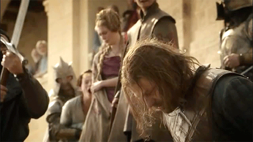 Gif retangular horizontal. Cena da série Game of Thrones. O gif mostra o momento em que o personagem Ned Stark está esperando para ter sua cabeça cortada por uma espada, em praça pública.