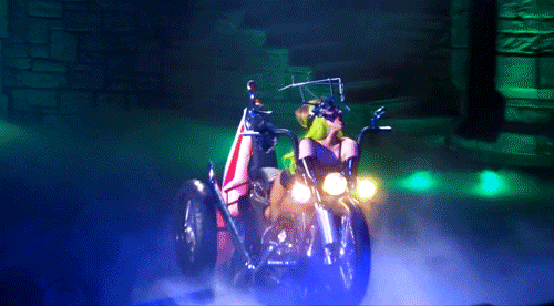 O gif mostra Lady Gaga em cima de uma moto durante a performance de Heavy Metal Lover na Born This Way Ball. Ela está andando pelo palco.