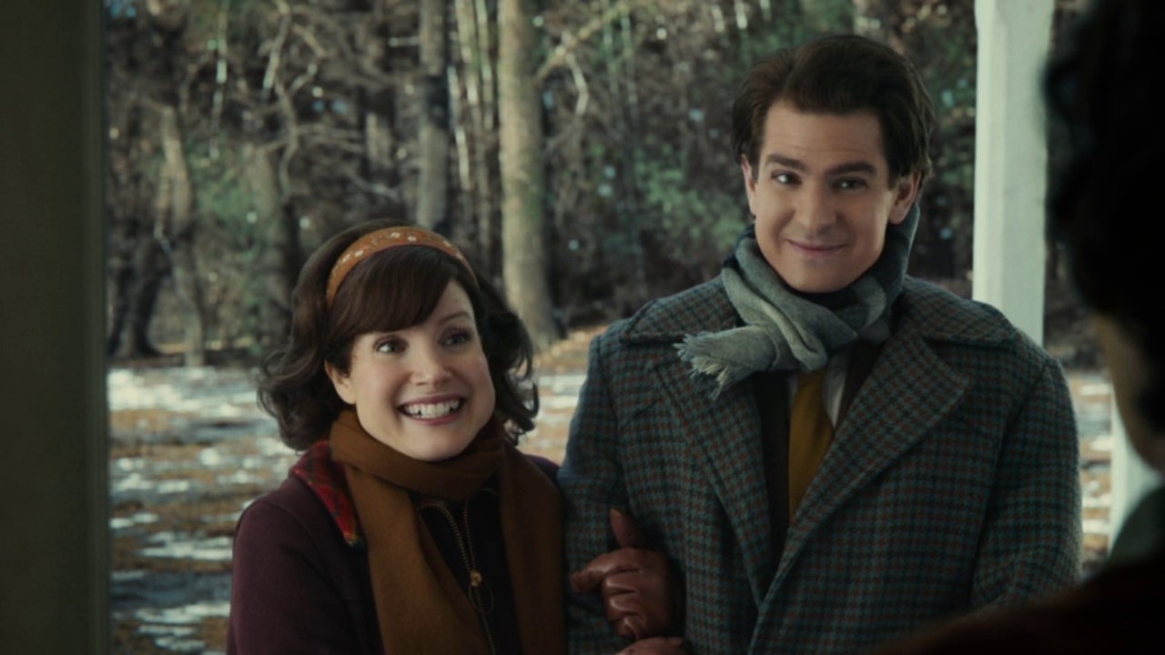 Cena do filme Os Olhos de Tammy Faye. Mostra um casal adulto, branco, sorrindo na varanda de uma casa. Eles usam roupas de frio, com casacos e cachecóis.