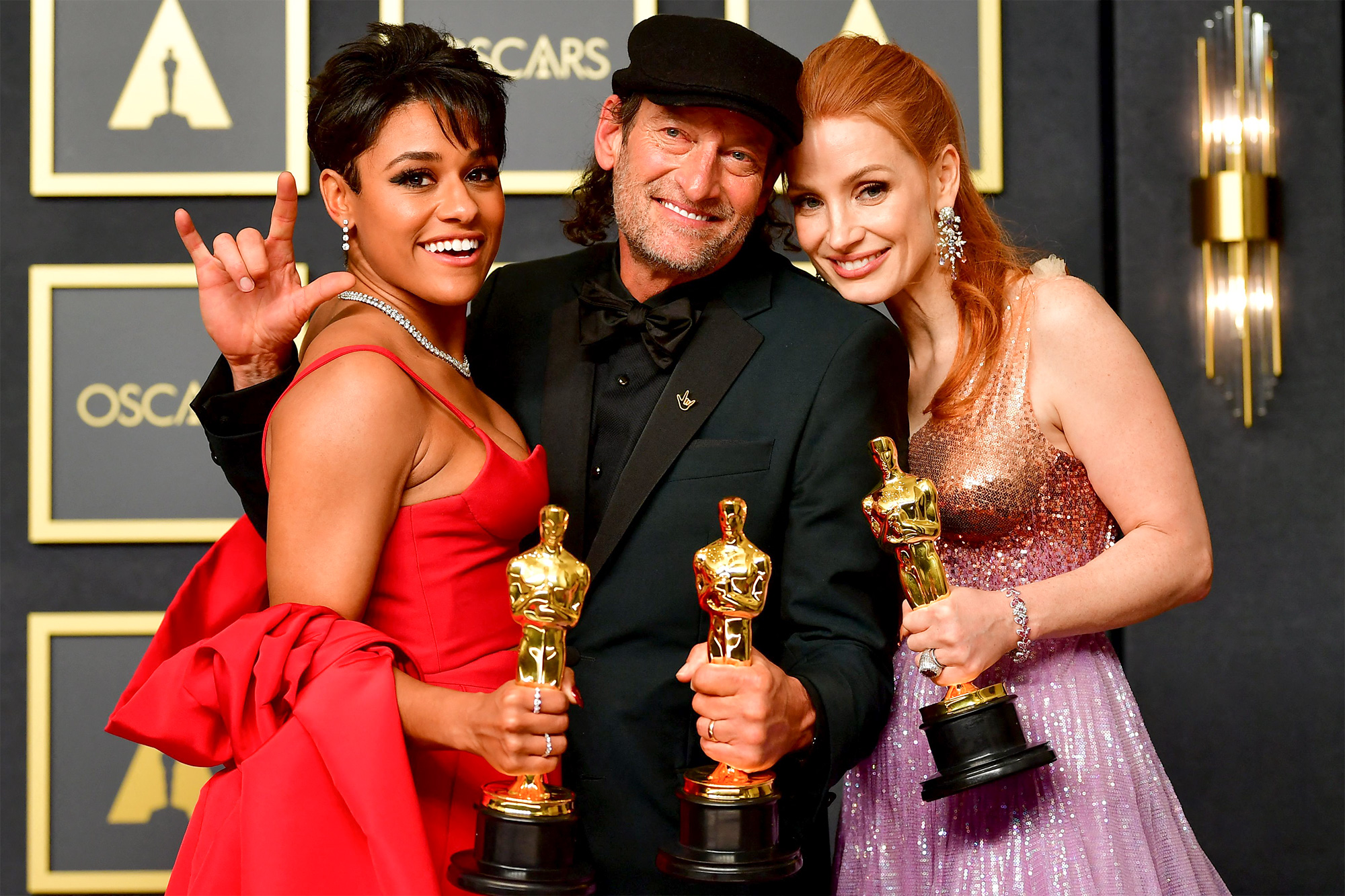 Foto dos atores Ariana DeBose, Troy Kotsur e Jessica Chastain posando com seus Oscars no tapete vermelho depois da cerimônia.
