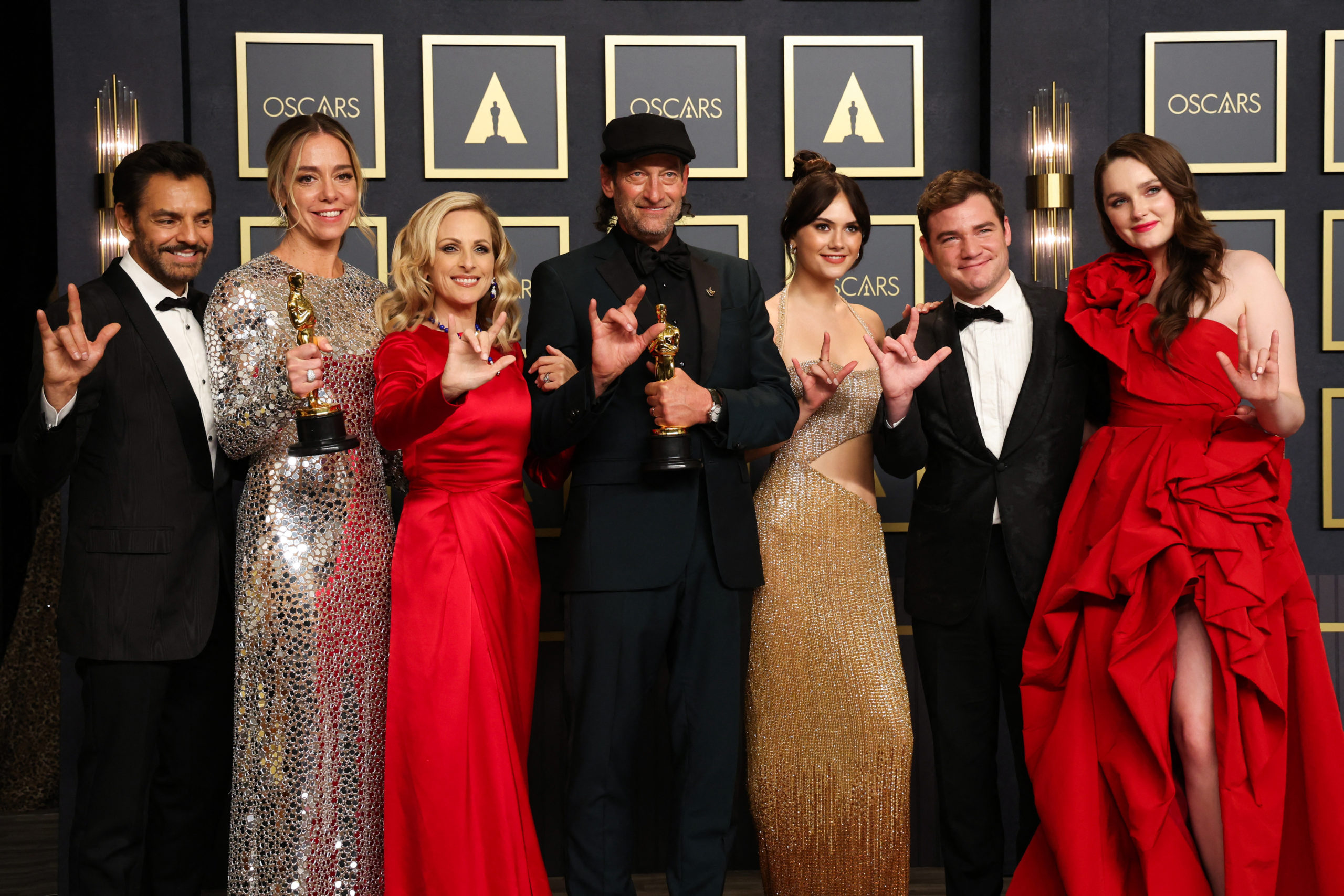 Foto do elenco do filme CODA posando no tapete vermelho com seus 2 Oscars.