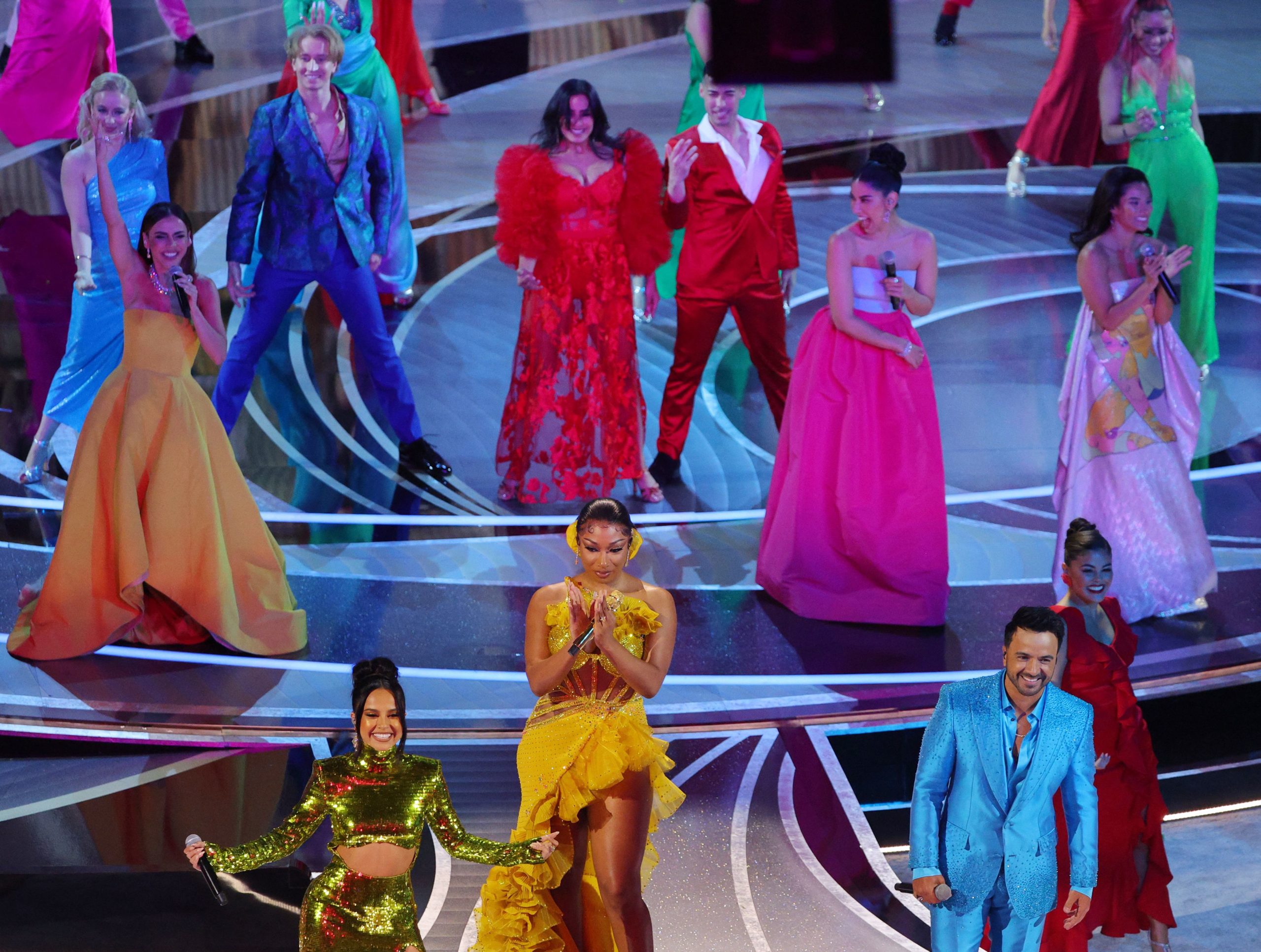 Foto da apresentação da música We Don't Talk About Bruno, no palco do Oscar 2022. Na foto, vemos várias pessoas cantando e posando, usando roupas coloridas.