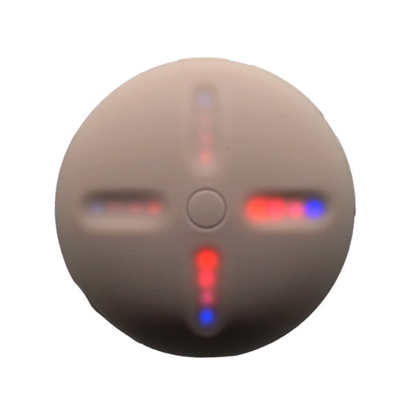 Imagem quadrada de fundo branco. No centro está um Stem Player, um dispositivo auditivo com formato arredondado na cor bege. O dispositivo possui um botão redondo no centro e quatro linhas afundadas que saem desse centro e que brilham na cor vermelha, rosa e azul.
