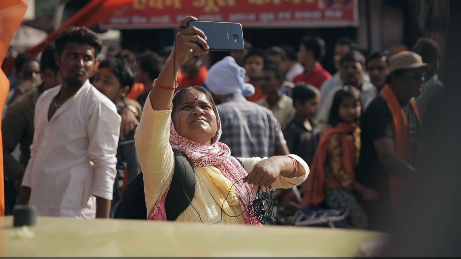 Cena do documentário Escrevendo com Fogo. A cena mostra uma mulher indiana filmando algo com o celular apontado para cima.