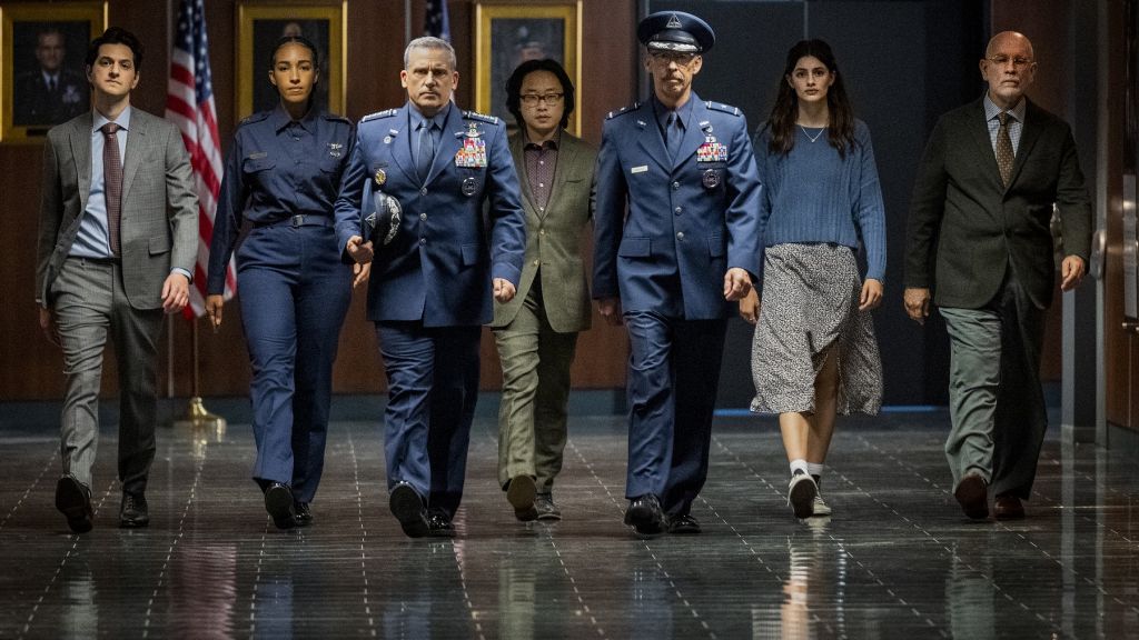 Cena da segunda temporada de Space Force mostra 7 pessoas caminhando. Entre homens e mulheres, eles usam ternos, uniformes oficiais de generais da NASA e uma garota veste blusa de moletom e saia cinza.