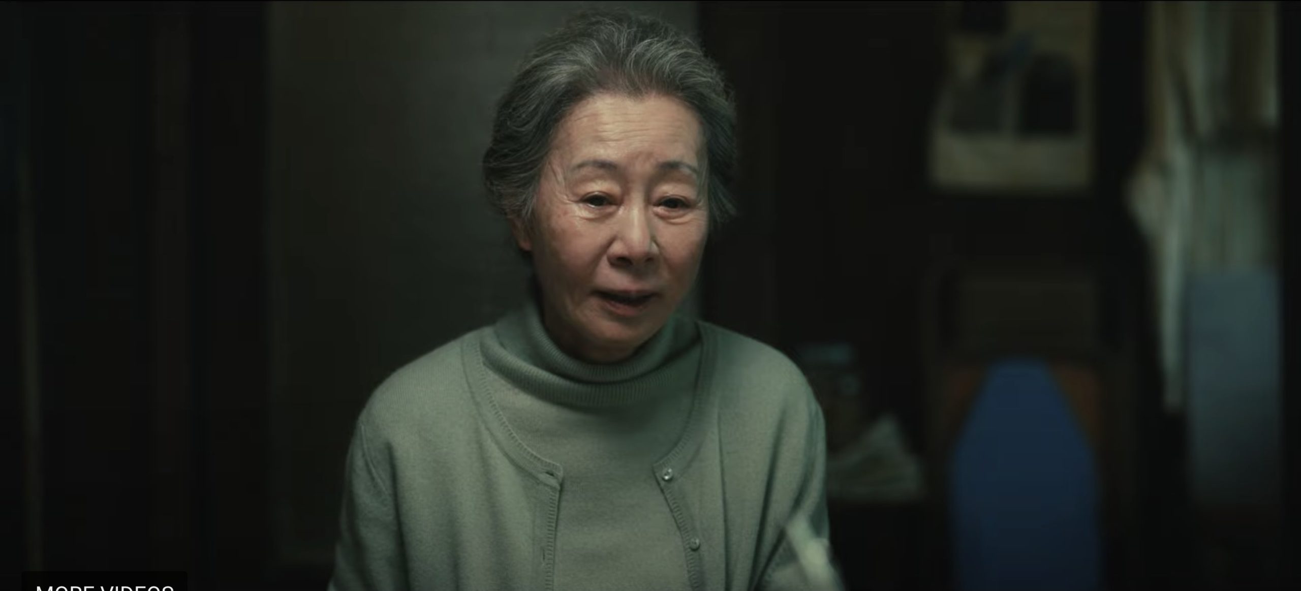 Cena da série Pachinko, mostra uma senhora idosa asiática sentada à mesa, usando roupas claras e de cabelos presos. 