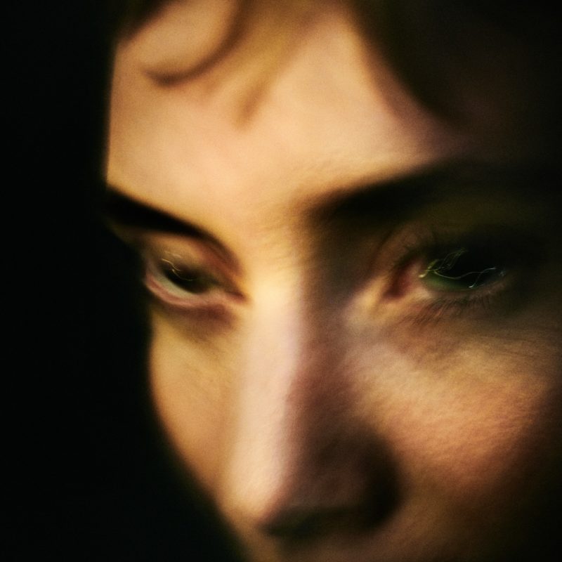 Capa do álbum EYEYE, de Lykke Li. A imagem mostra um close em seu rosto, sob um fundo escuro. A imagem está tremida. Ela é uma mulher branca, de olhos claros e cabelos escuros.