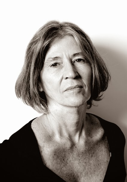 a escritora Elvira Vigna olha, em um retrato em preto e branco, à câmera. Com os cabelos soltos, um pouco acima da altura dos ombros, ela usa um vestido preto de gola aberta.