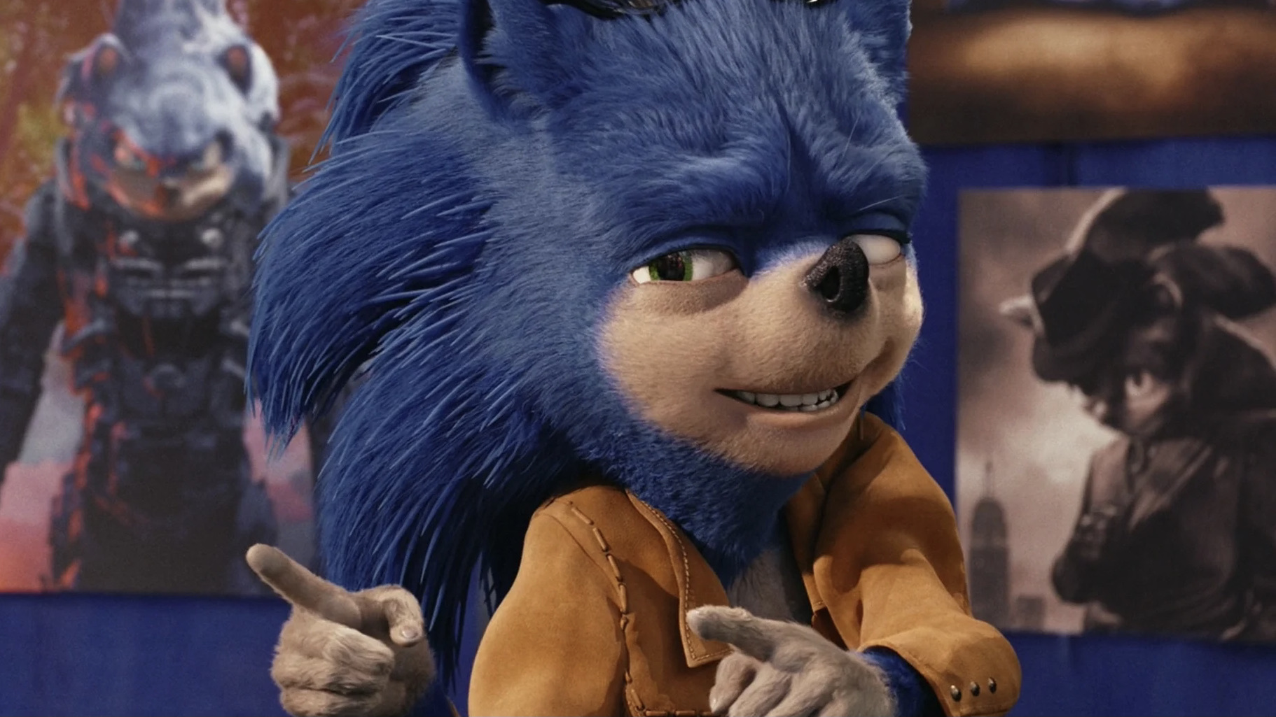 Cena do filme Tico e Teco: Defensores da Lei. No centro da imagem, temos o personagem Sonic Feio, um ouriço que tem pelo azul na região dos espinhos e pelo branco na região da boca, juntamente com focinho preto, olhos verdes e dentes brancos. Ele está vestindo uma jaqueta marrom clara e apontando com as duas mãos na direção esquerda para a câmera. Atrás dele, temos pôsteres que mostram o personagem como um herói de videogame de armadura grande acinzentada e como detetive noir em preto e branco vestindo um sobretudo. A cena acontece durante o dia.