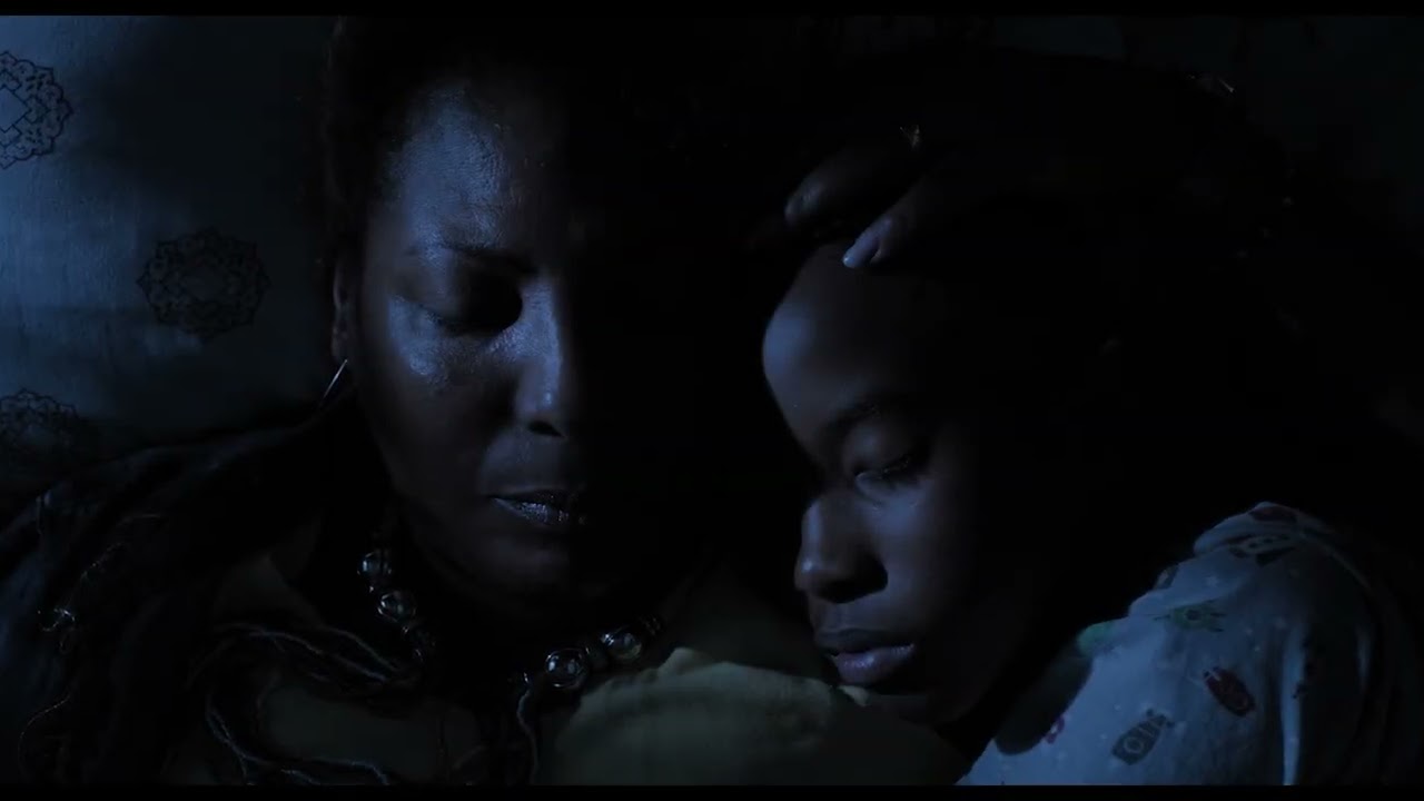 Cena do filme Marte Um, a imagem mostra uma mulher adulta e uma criança negras dormindo sob a luz azul do luar.