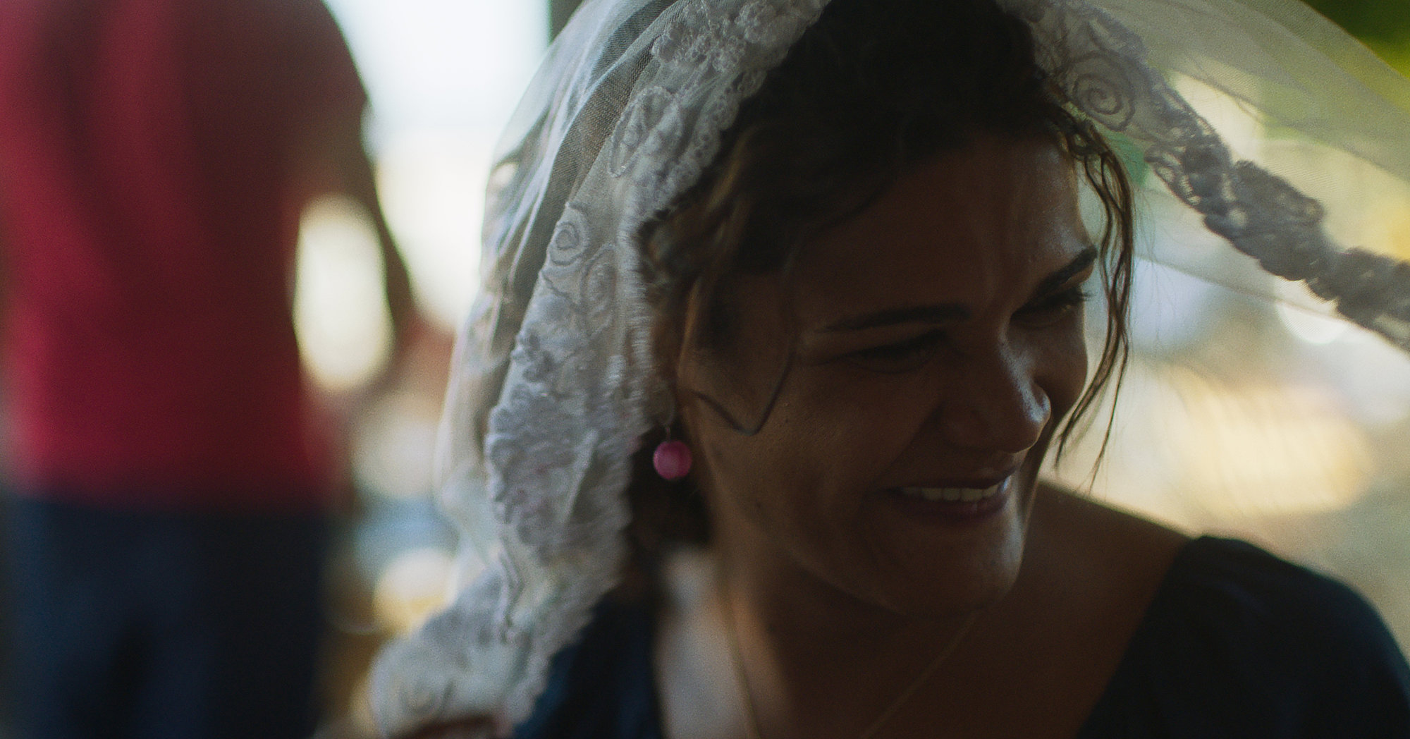 Cena do filme Paloma, mostra a protagonista, uma mulher negra, sorrindo com um véu branco na cabeça. 