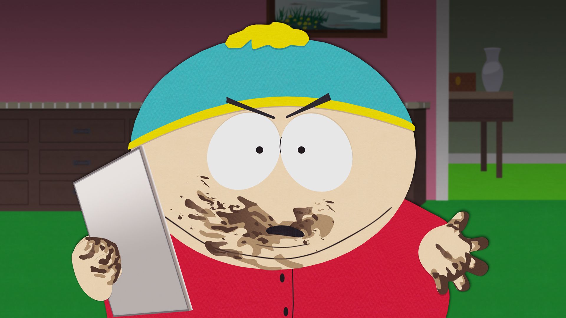 Cena da série South Park apresenta Eric Cartman no plano central da imagem, um menino branco, com sobrepeso, que usa um gorro de inverno azul e amarelo, um casaco vermelho e está segurando um tablet prateado com as mãos e boca sujas de chocolate. Sua expressão é de braveza. No fundo aparece sua casa, com paredes rosa e piso verde.