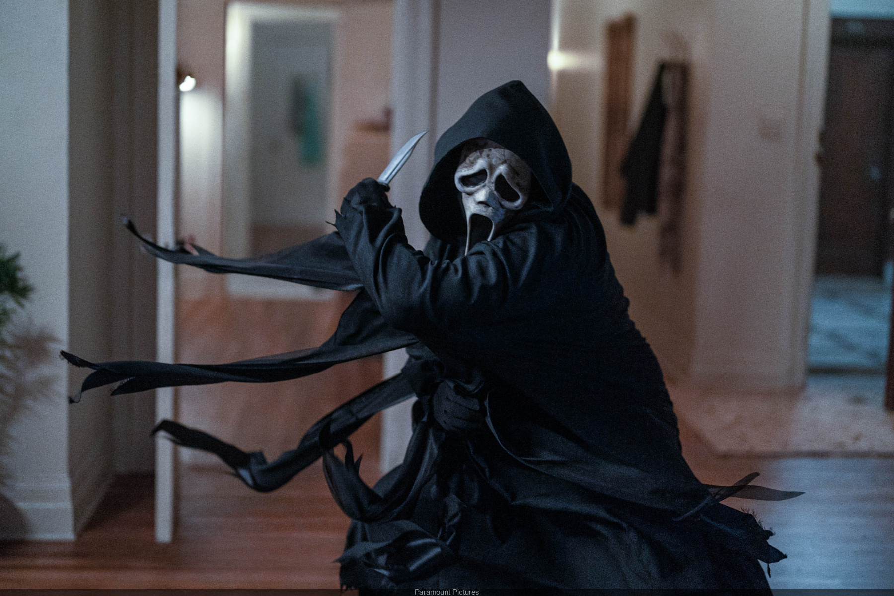 Cena do filme Pânico 6. Nela, encontra-se o assassino Ghostface com uma faca. Sua fantasia consiste em um manto preto e uma máscara branca com rosto deformado.