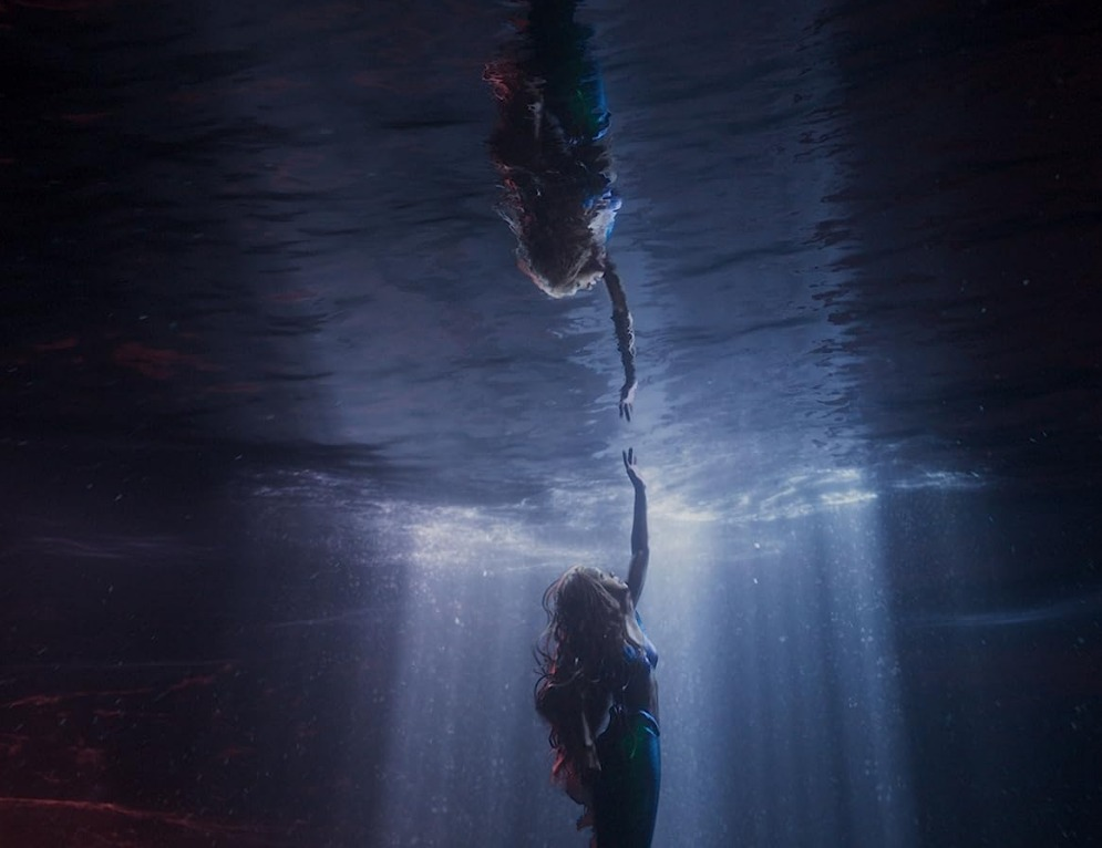  Cena do filme A Pequena Sereia. Nela, observa-se a personagem Ariel dentro do mar olhando o seu reflexo através da água.