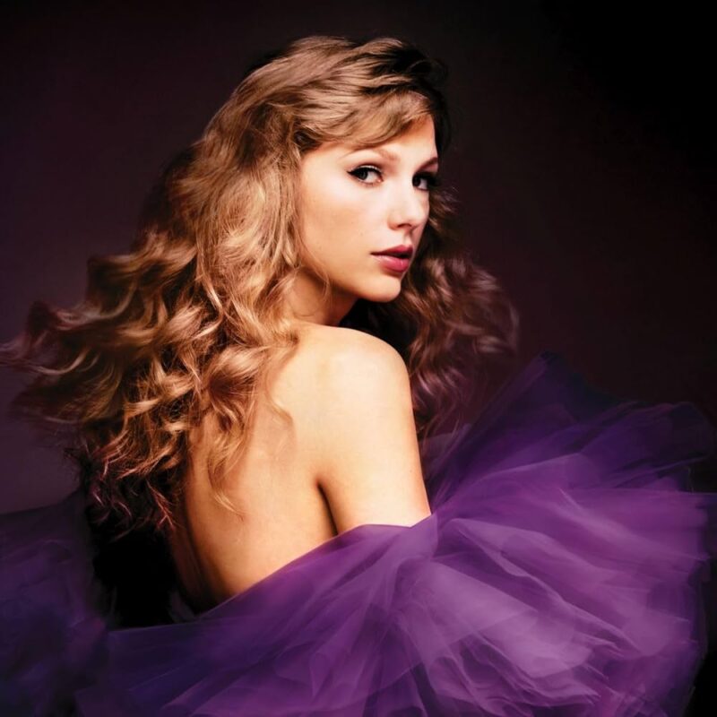 Capa do álbum Speak Now (Taylor’s Version), em que Taylor, uma mulher branca de cabelos loiros e compridos, está de costas olhando pelo ombro para frente, com os cabelos em movimento e usando um vestido roxo em um fundo escuro.