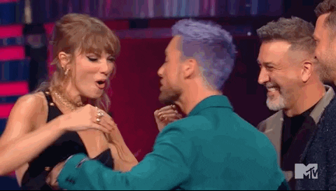 Imagem em movimento de Taylor Swift, mulher branca e os membros do grupo ‘N Sync, homens brancos, interagindo entre si no palco do VMAs. Eles estão entregando a estatueta de vitória para a cantora.