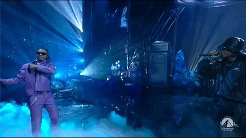 Imagem em movimento de dois homens cantando no palco do VMAs. A imagem mostra Metro Boomin, que veste um conjunto roxo com uma camisa branca e um colar de cruz e Future, que usa um conjunto e chapéu pretos. 