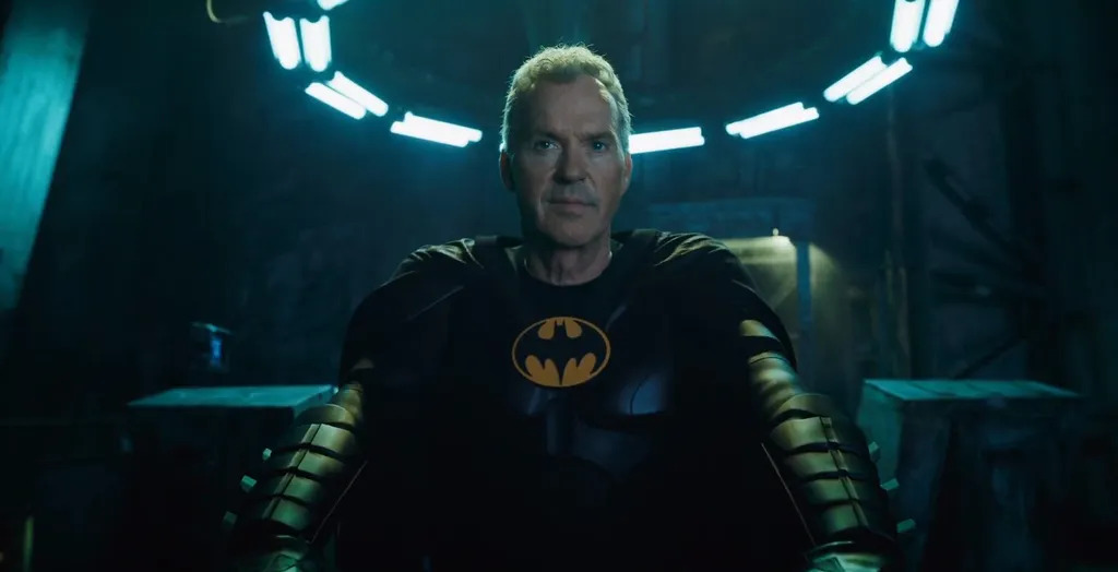 Cena do filme The Flash. Na imagem, Michael Keaton, homem branco intérprete do Batman, usa um traje preto com um símbolo de um morcego da mesma cor no centro do uniforme. 