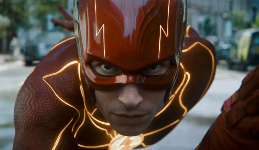 Cena do filme The Flash. Na imagem, Ezra Miller, pessoa não binárie que interpreta Flash, usa um traje vermelho com raios ao longo do uniforme. Ele está sério e em posição de corrida. 