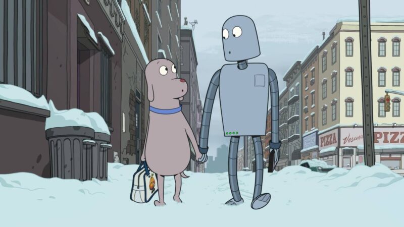 Cena de Robot Dreams. Na imagem, o cachorro e o robô andam pela neve. Ambos são cinzas e estão de mãos dadas. Ao fundo, há diversos prédios cinzas. 