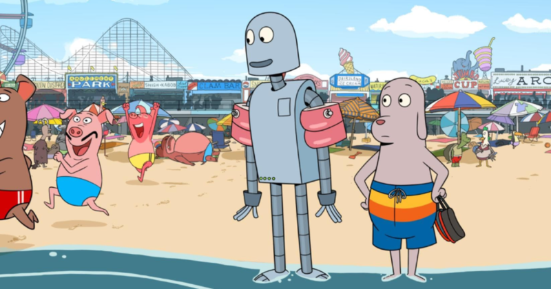 Cena de Robot Dreams. Na imagem, o robô e o cachorro estão com os pés na beira da praia. Os dois são cinzas. O robô veste uma boia de braço rosa e o cachorro um short nas cores azul, amarelo e laranja. Ao fundo há areia e diversas barraquinhas de praia.
