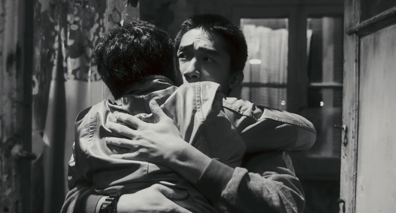 Em uma imagem em preto e branco, Leslie Cheung e Tony Leung se abraçam, seus olhares revelando confusão diante das adversidades do relacionamento.