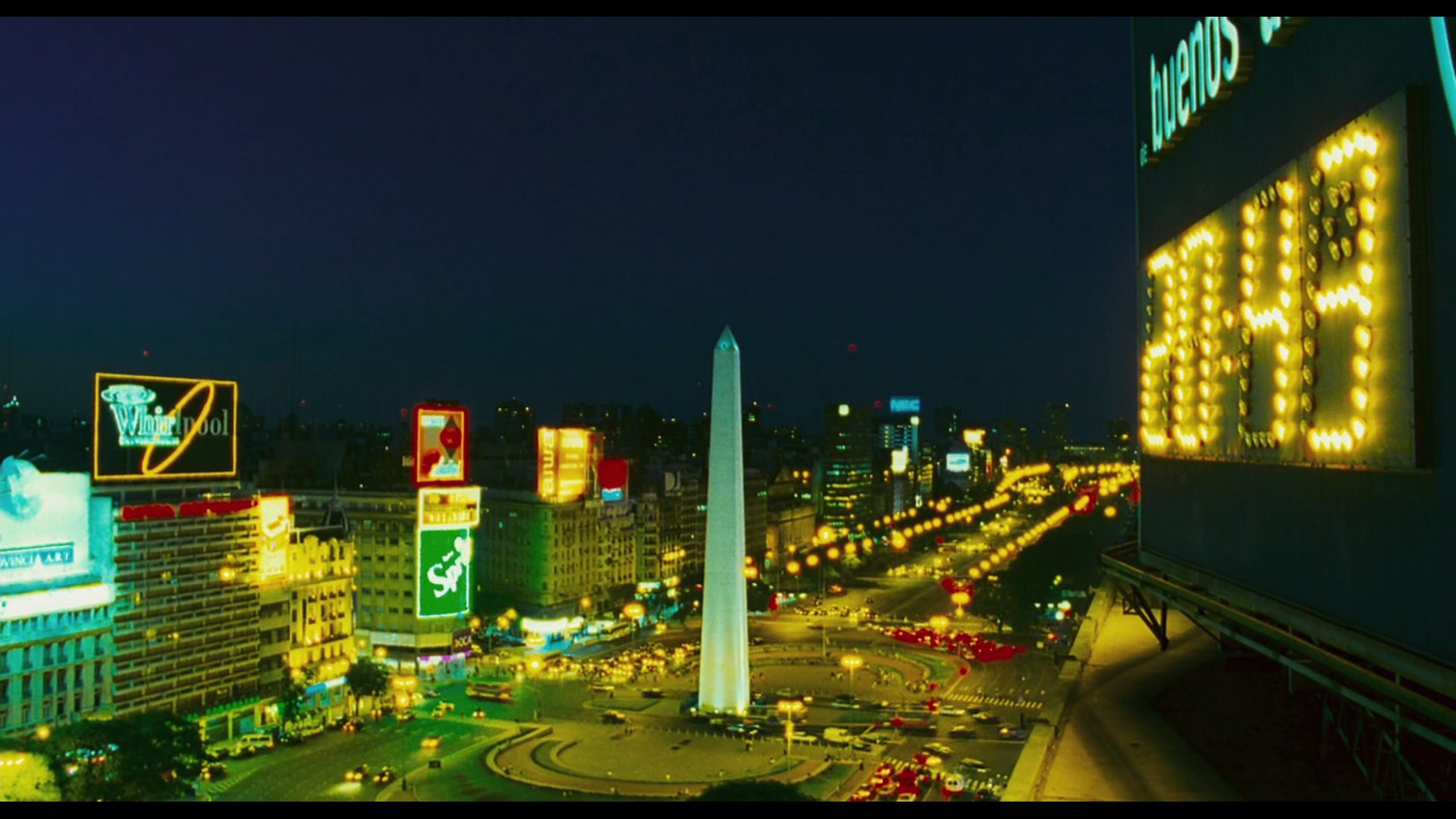 Ao fundo da agitada Buenos Aires, as luzes neon iluminam a cidade enquanto um relógio marca 20h43